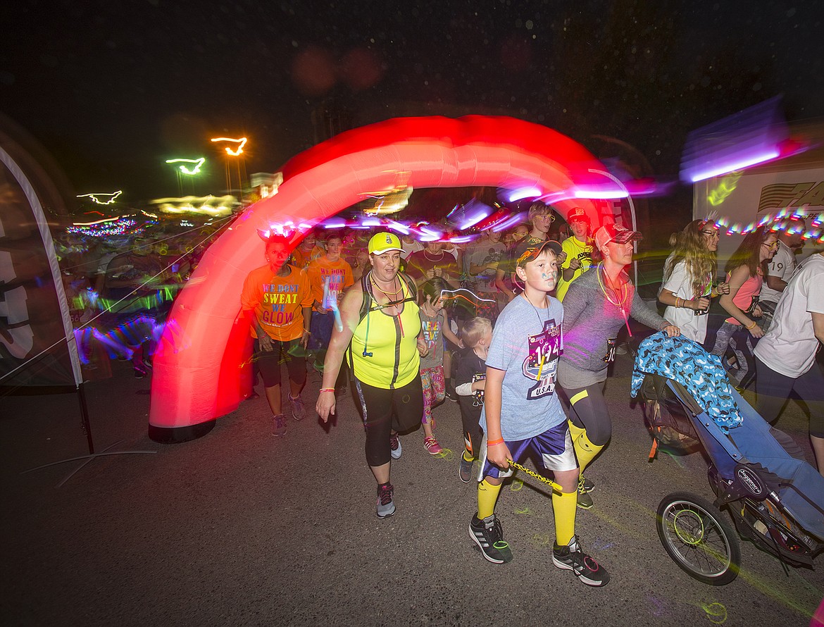 Racers run off the start line in the Glacier Glow Run in Columbia Falls in 2016. Nearly 600 ran in the event. (File photo)