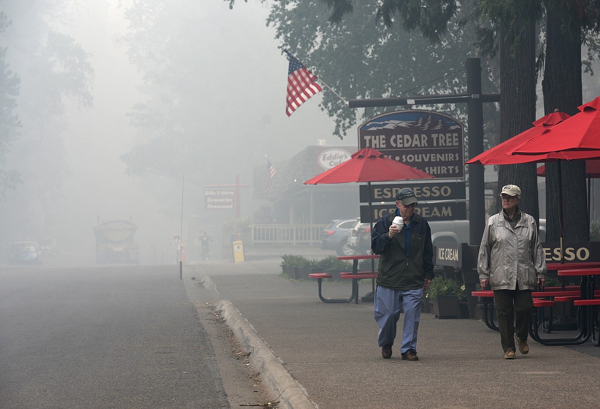 A few tourist walk down a smoke-filled street at Apgar Village on Tuesday.