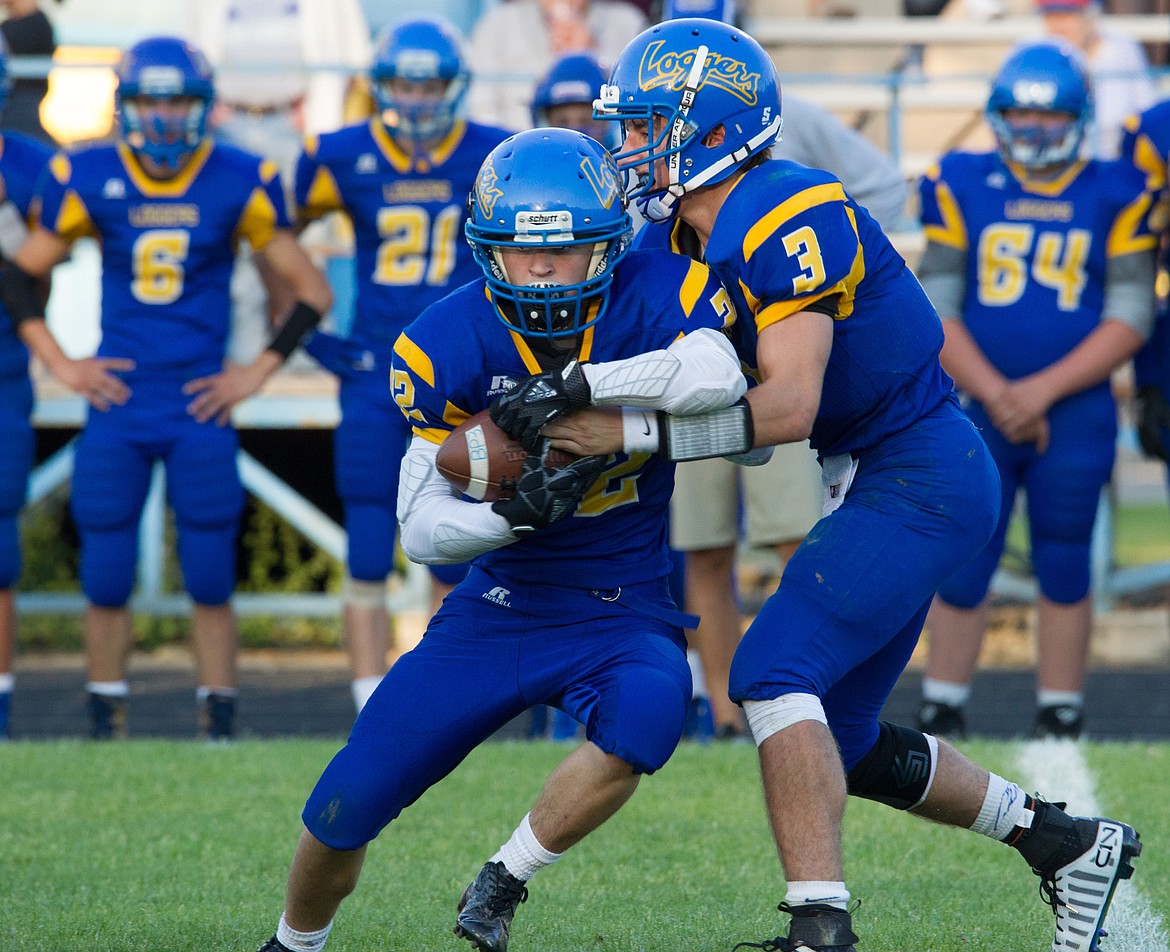 Libby Quarterback Brian Peck, right, hands off to Drew Ginther in a game against Corvallis Friday night in Libby.