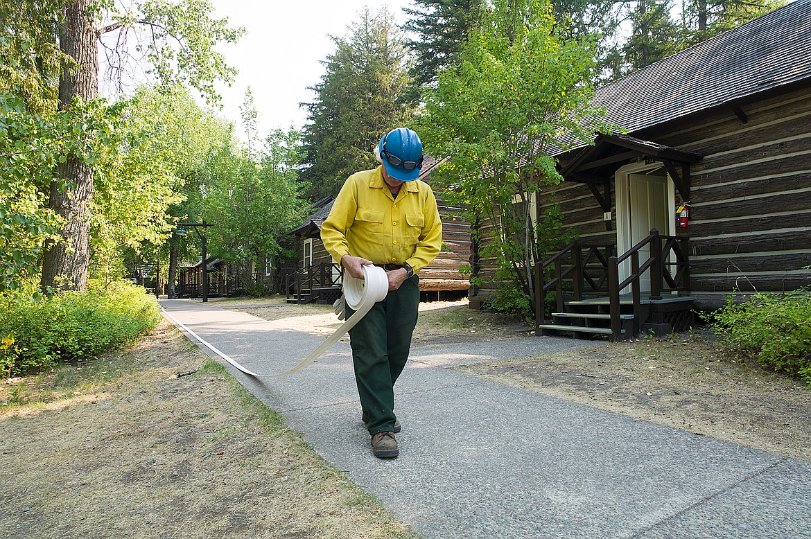 Firefighter Jeff Rajowski lays down hose at the cabin complex adjacent to Lake McDonald Lodge on Saturday.