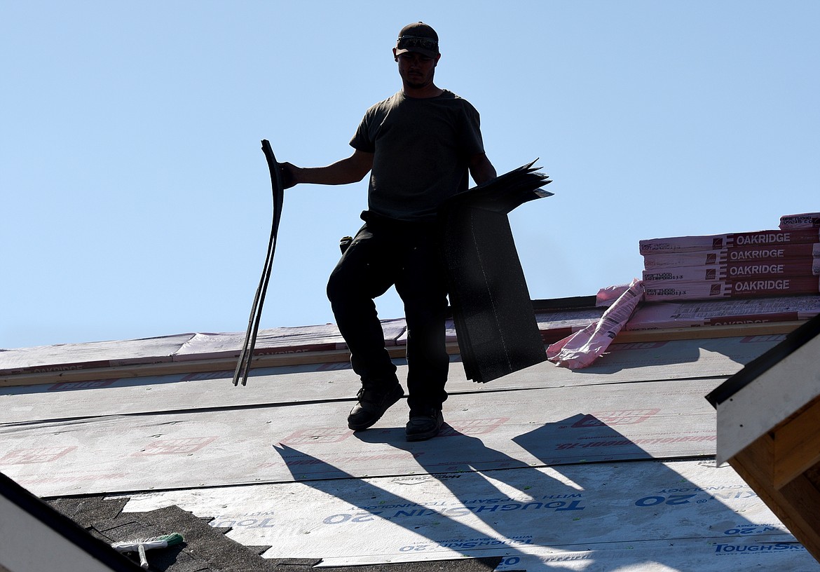 Jon Mooney carries shingles as he works on a roof in west Kalispell on Friday. (Aaric Bryan photos/Daily Inter Lake)