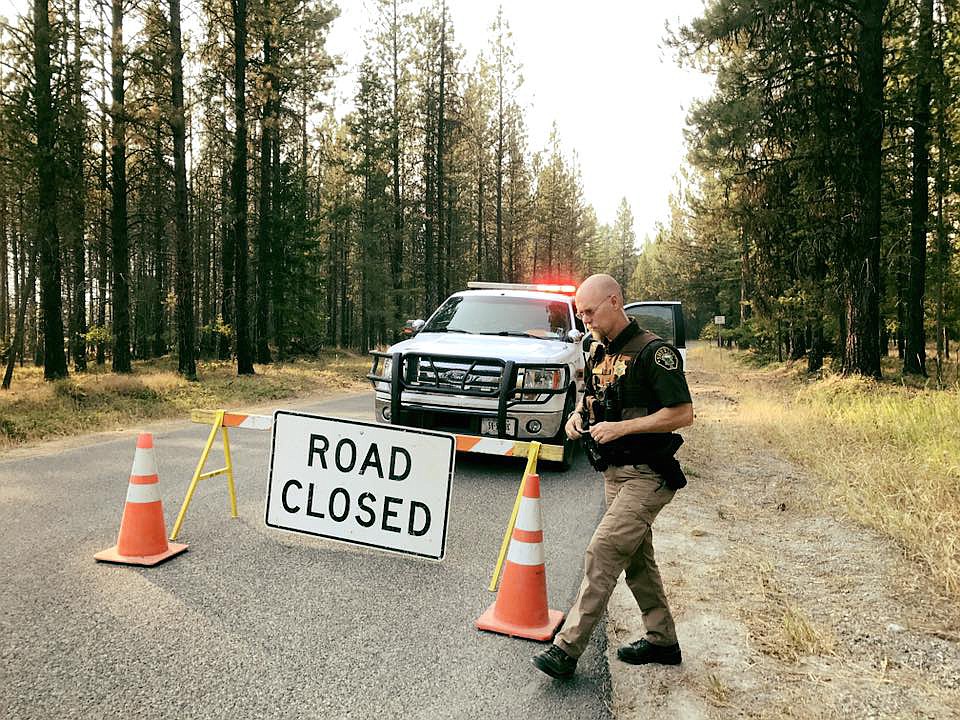 Lincoln County Sheriff's Deputy Brent Faulkner mans a roadblock on the Pipe Creek Road side of Bobtail Cutoff Saturday evening. The road was closed due to the West Fork fire. (Paul Sievers/The Western News)