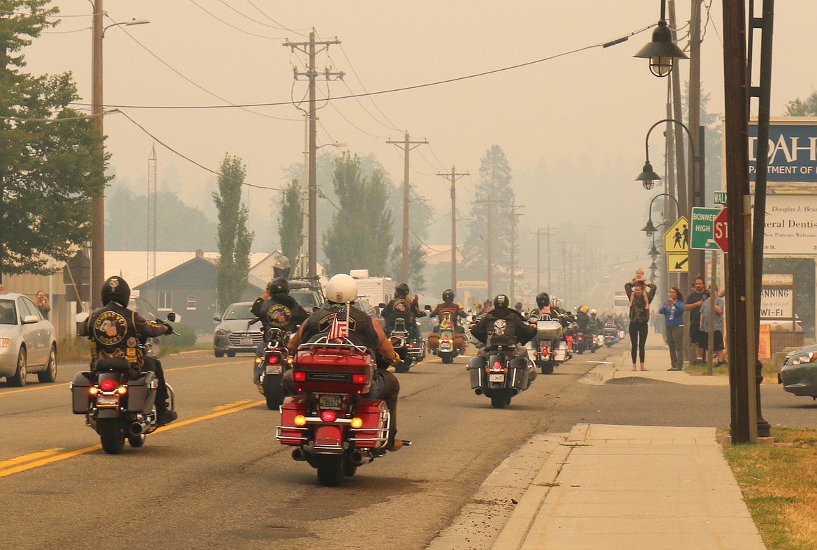 Onlookers watch as the long line of bikers rides along with the traveling Wall That Heals memorial, en route to Kalispell, Mont.