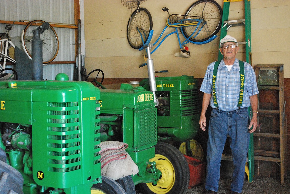 Bob Kirkpatrick/The Sun Tribune - Jim stands beside three of his nine vintage restored John Deere tractors.