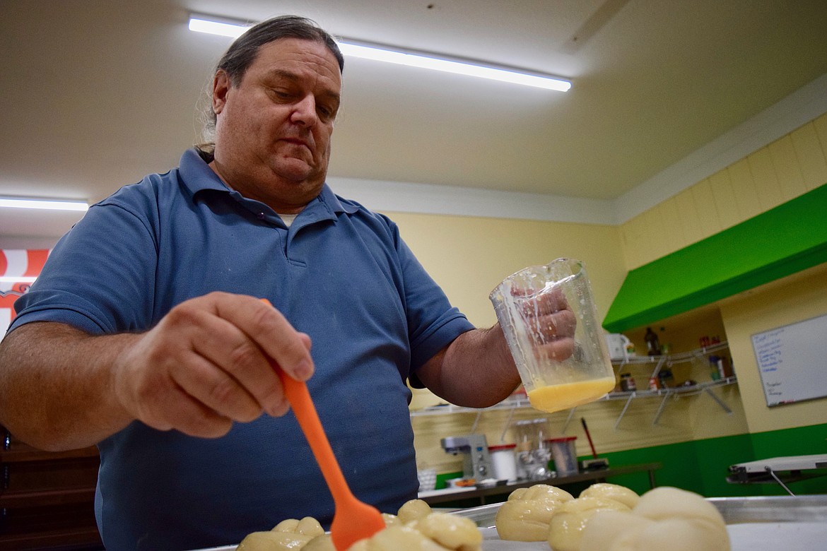 Charles H. Featherstone/Columbia Basin Herald
Baur Bakery employee Michael Viglione spreads an egg glaze on rolls Thursday morning as the bakery prepares to open today.