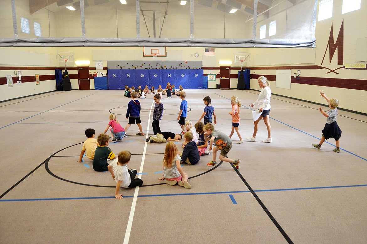 Students enter the Muldown Elementary gym on a recent morning to begin health enhancement lessons. A curtain was installed in the center of the gym to divide the space. Enrollment numbers at the school require that two classes use the gym at one time. (Heidi Desch/Whitefish Pilot)