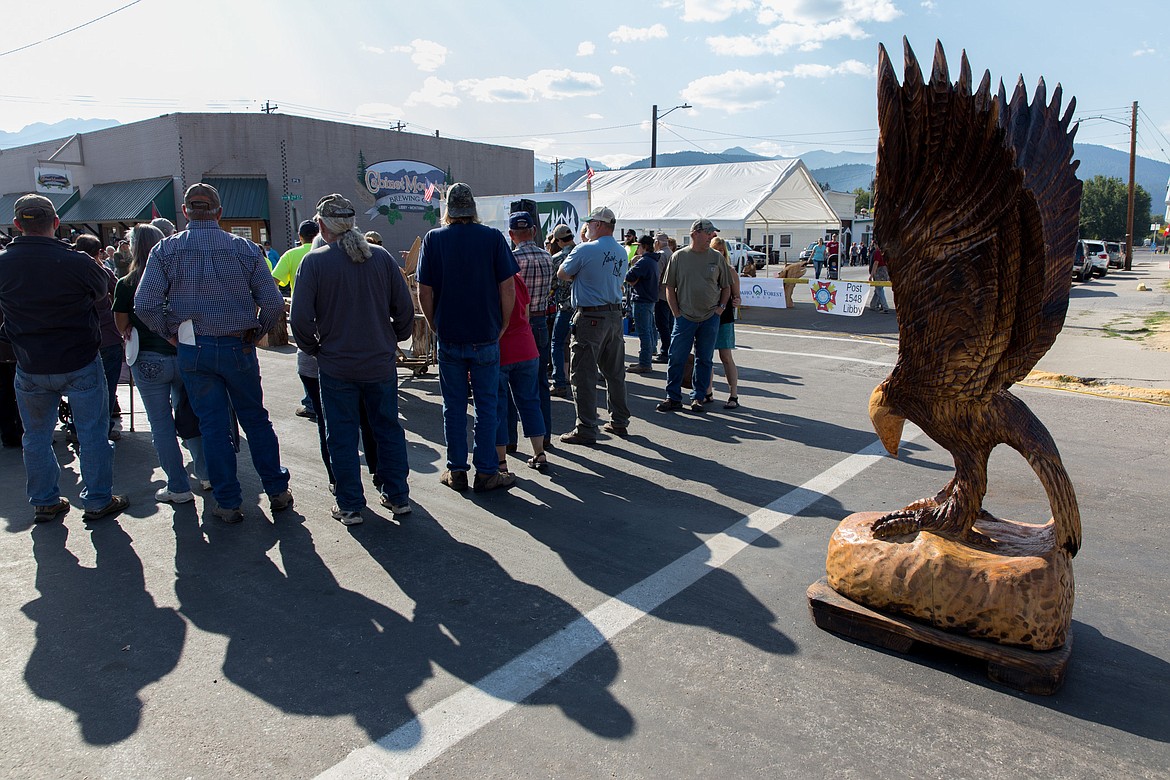 Spectators on Saturday attend an auction of wood carvings. The eagle at right, carved by event emcee Steve Backus, was a raffle prize.