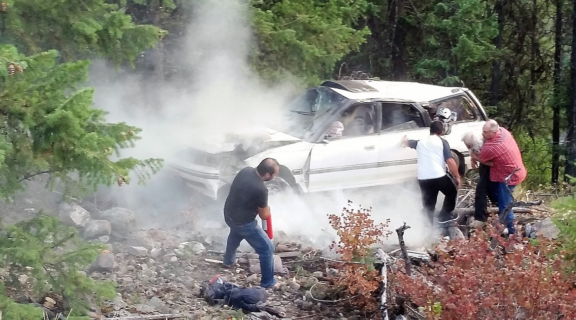 Two men help to get a 71-year-old Tarkio man out of his burning car after it went over an embankment. (Photo by Chadly Johnson)