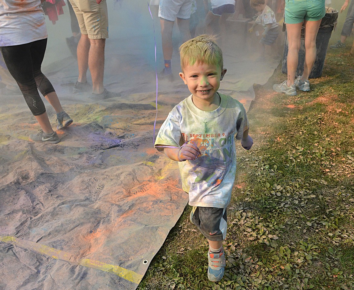 Senna Campbell, 4, runs through the flying powdered colors Saturday during the color toss at Depot Park for the Whitefish Community Foundation Color Run and Nonprofit Fair. (Heidi Desch/Whitefish Pilot)