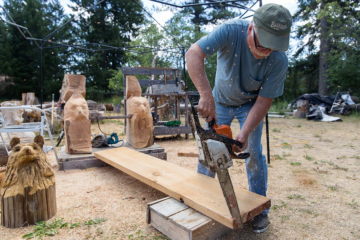 Ron Adamson uses a chainsaw to carve the back of a bench he was commissioned to create at his Libby home in July. (John Blodgett/The Western News)