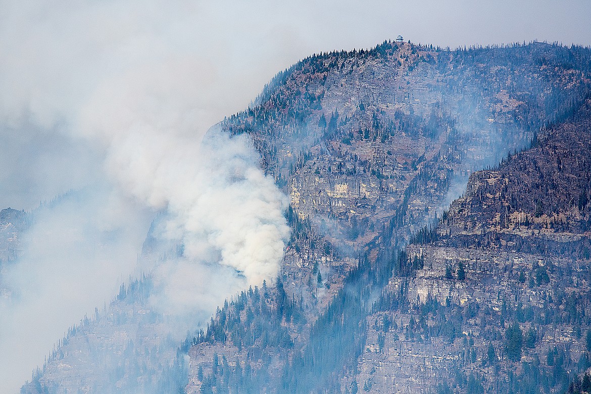 The flanks of Mount Brown burn Sunday in the Sprague Fire, but the lookout, wrapped in fire resistant material, remains.