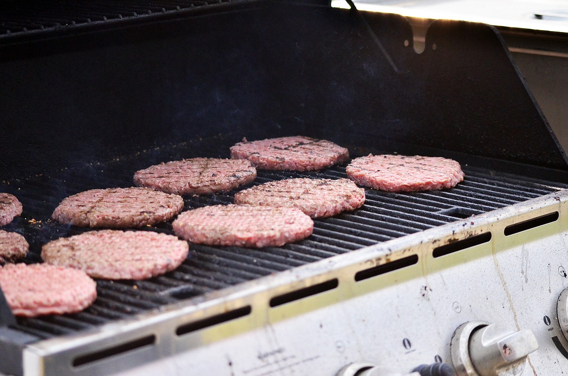 Del Smith cooking up some delicious burgers on the BBQ for event goers. (Erin Jusseaume/ Clark Fork Valley Press)