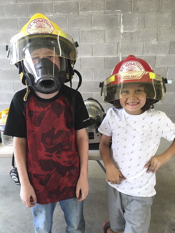 Ronson Hout, left and Isaac Morgeau, right, try on firefighter gear during the St. Ignatius Volunteer Fire Department openhouse over the weekend. (Photo courtesy of the St. Ignatius Volunteer Fire Department)