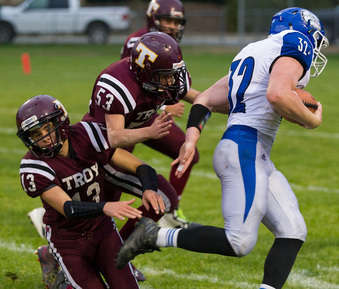 St. Ignatius running back Gus Bosley, right, evades Troy's Ricki Fisher, left, and Brodie Gravier Friday night in Troy. (John Blodgett/The Western News)