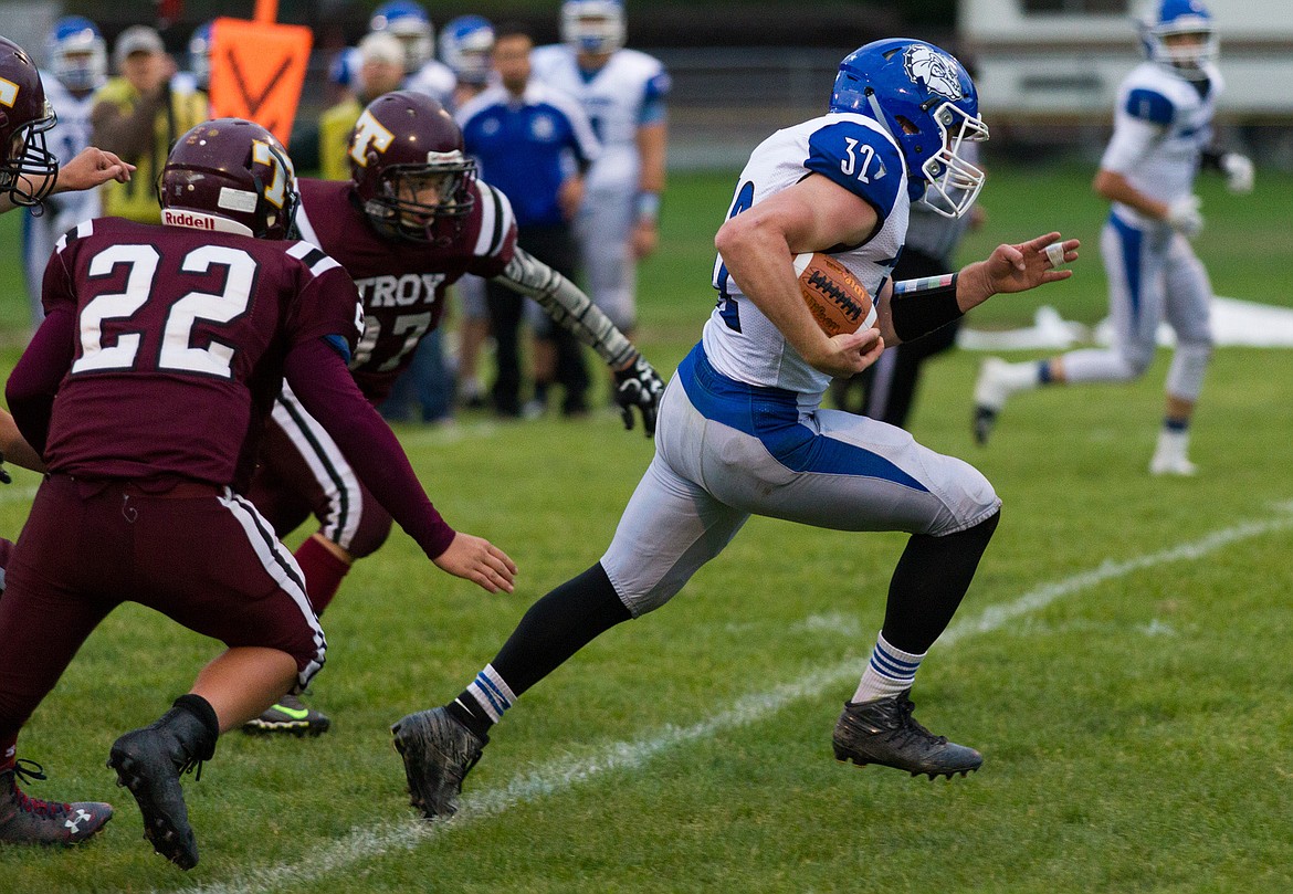 St. Ignatius running back Gus Bosley, right, evades Troy's Cy Winslow, left, and Alex Harper Friday night in Troy. (John Blodgett/The Western News)