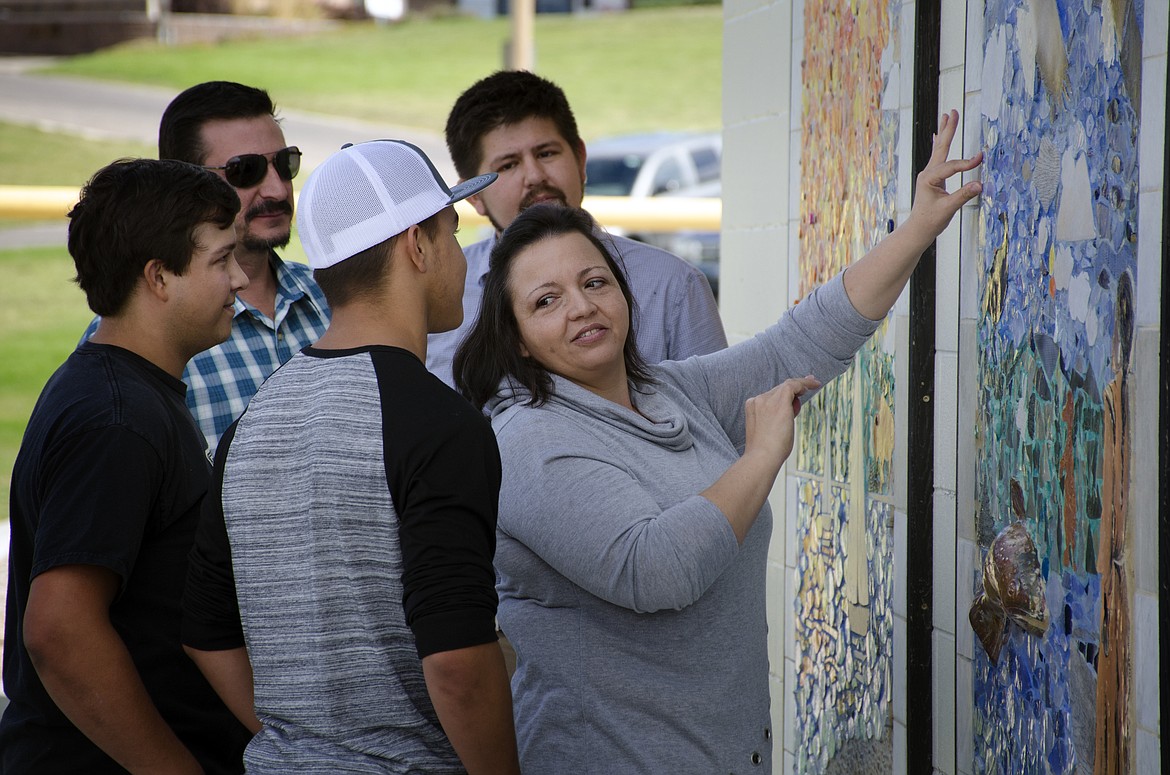 Terri Cleveland places the final piece into the new mosaic at Riverside Park Sunday, a cast of the Polson Police badge of her late husband, William Cleveland. Looking on are her sons, Nick and David, as well as project designer Cameron Decker and artist Matt Holmes. (Jeremy Weber/Lake County Leader)