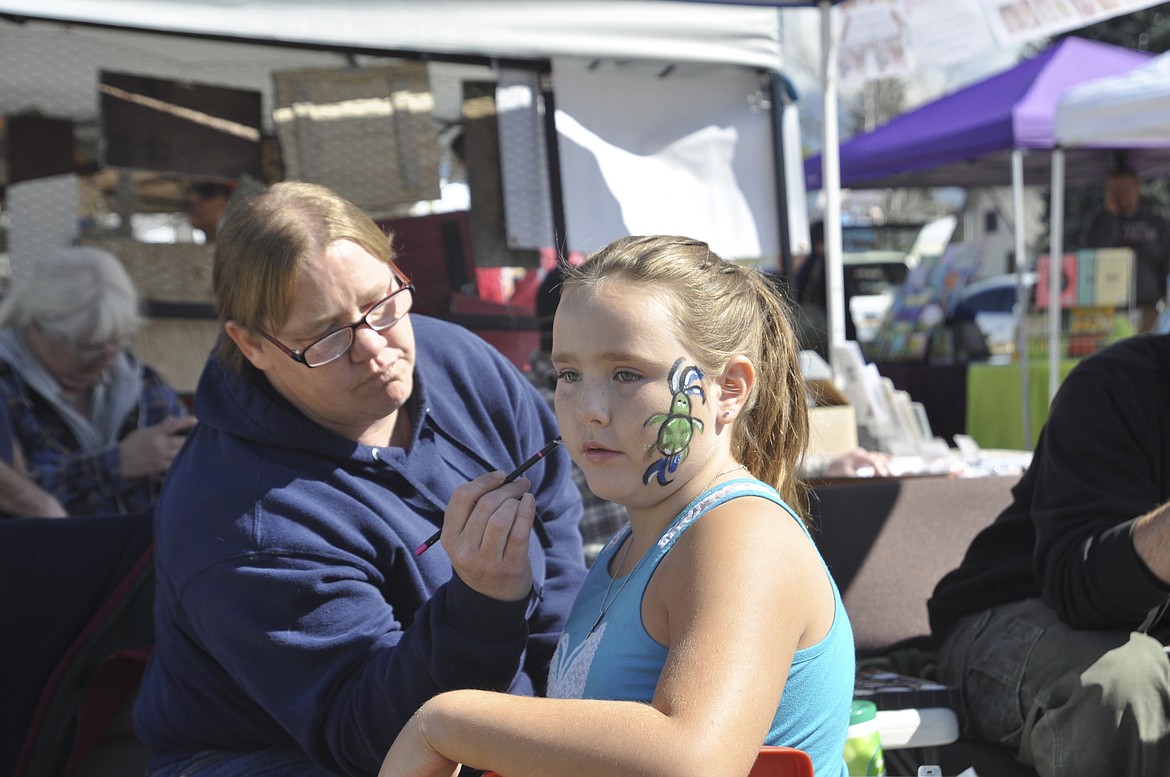 Linda Smith of the Ronan Library District concentrates as she does a face painting for Lainey Johnson, 8, of Ronan. Lainey had a turtle painted then decided she wanted to add a rainbow. (Ashley Fox/Lake County Leader)