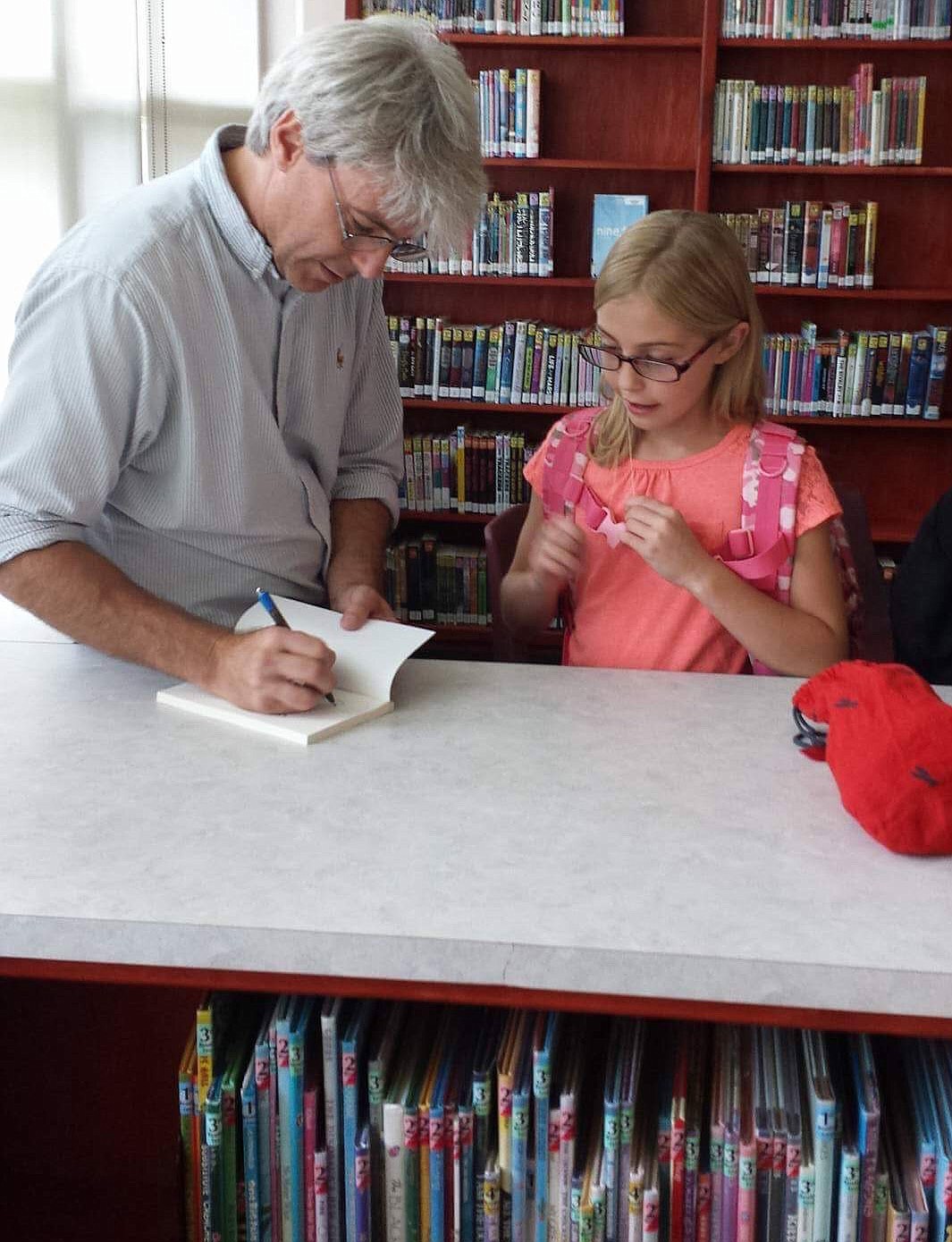 Author Jimothy Newton signs a book for Morrison Elementary fourth grader Mellissa Laffoon at the school in Troy on Monday. Newton was on tour for his self-published book "Baldilocks and the Three Dares," the proceeds of which go to children's charities. (Photo by Stacy Walenter)