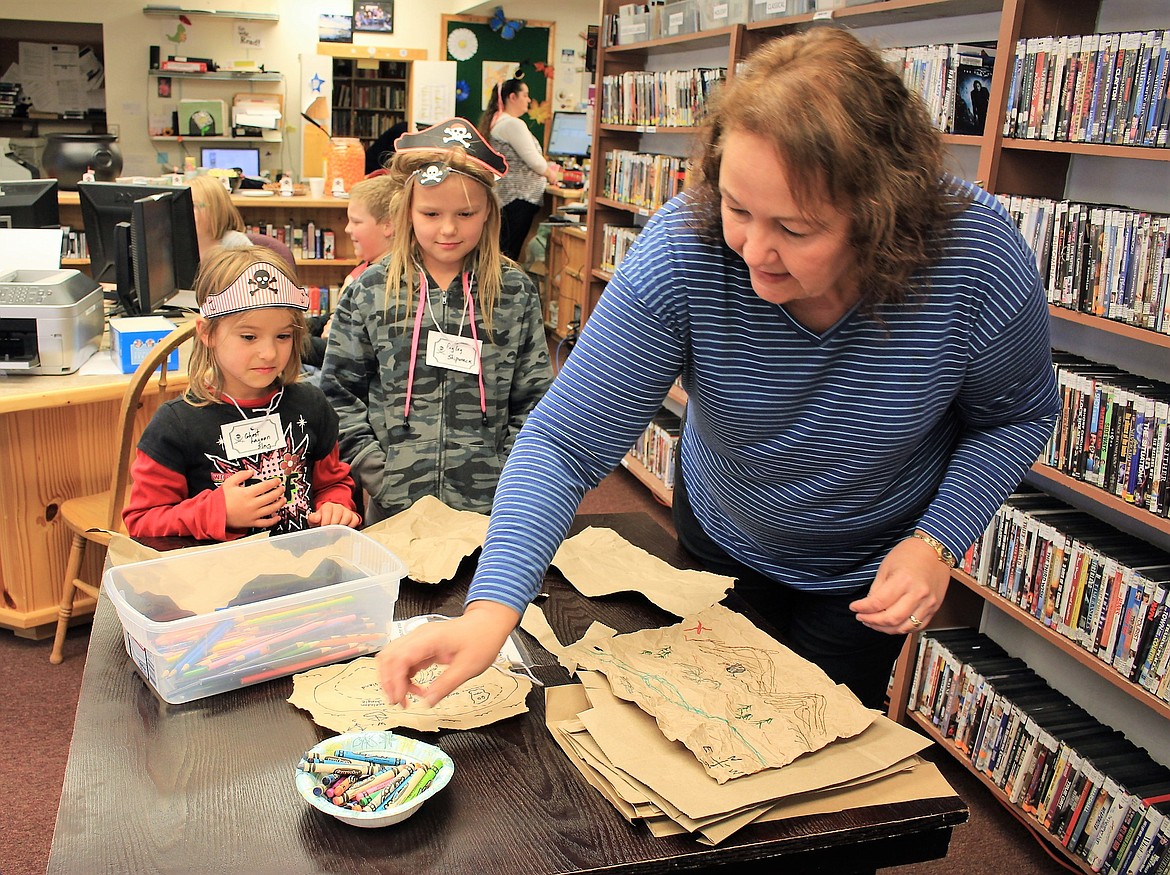 Florence Evans (Fishy Slappy McGee) helps two treasure hunters, Karissa Pierce, 5, (Ghost Lagoon Slag ) and Karina Pierce, 8, (Pegleg Shipwreck) create their own treasure map during Talk Like a Pirate Day on Sept. 19. (Kathleen Woodford/Mineral Independent)