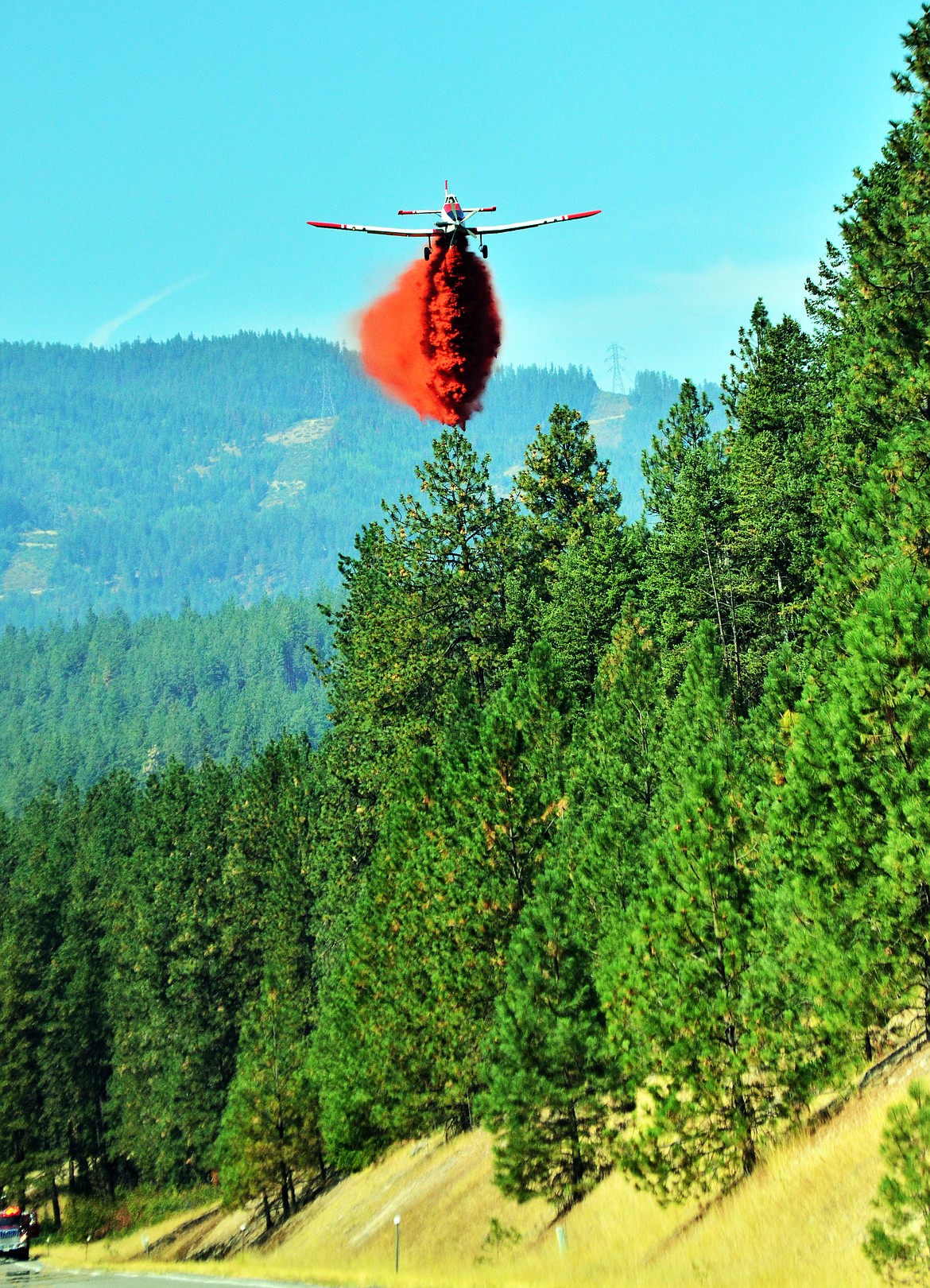As a ground crew readies for back up a fixed air plane drops a load of retardant on one of the fires on Highway 135. (Erin Jusseaume/ Clark Fork Valley Press)
