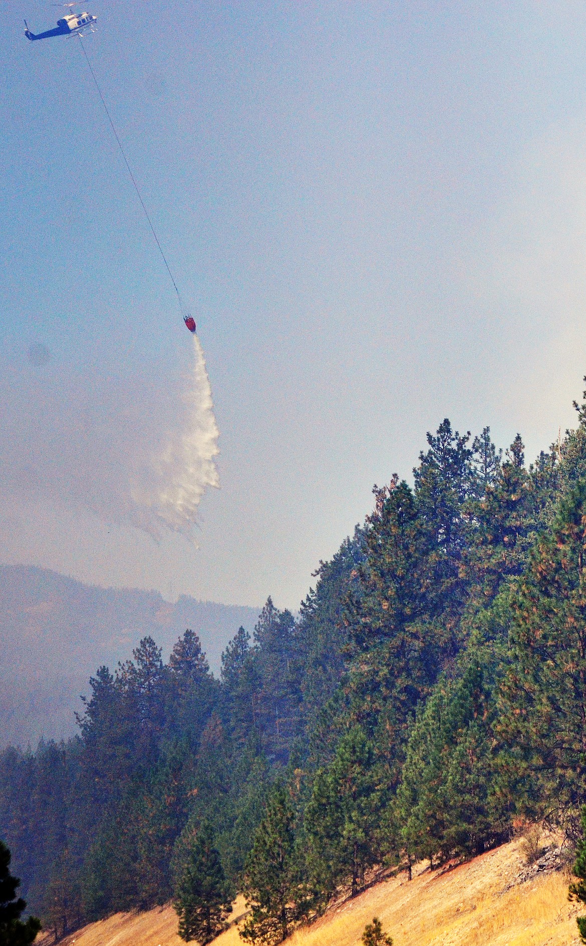 A shot of one helicopters maneuver to douse the flames with water over one fire on Highway 135 (Erin Jusseaume/ Clark Fork valley Press)