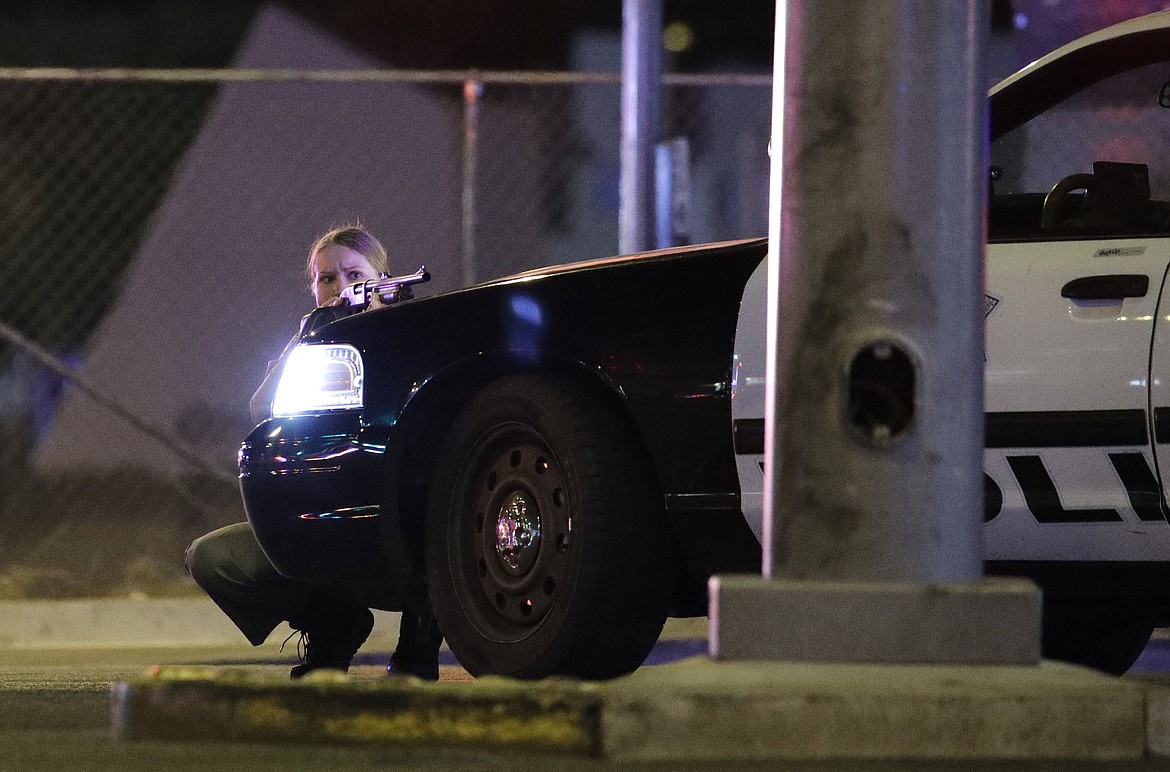 A police officer takes cover behind a police vehicle during a shooting near the Mandalay Bay resort and casino on the Las Vegas Strip, Sunday, Oct. 1, 2017, in Las Vegas. (AP Photo/John Locher)