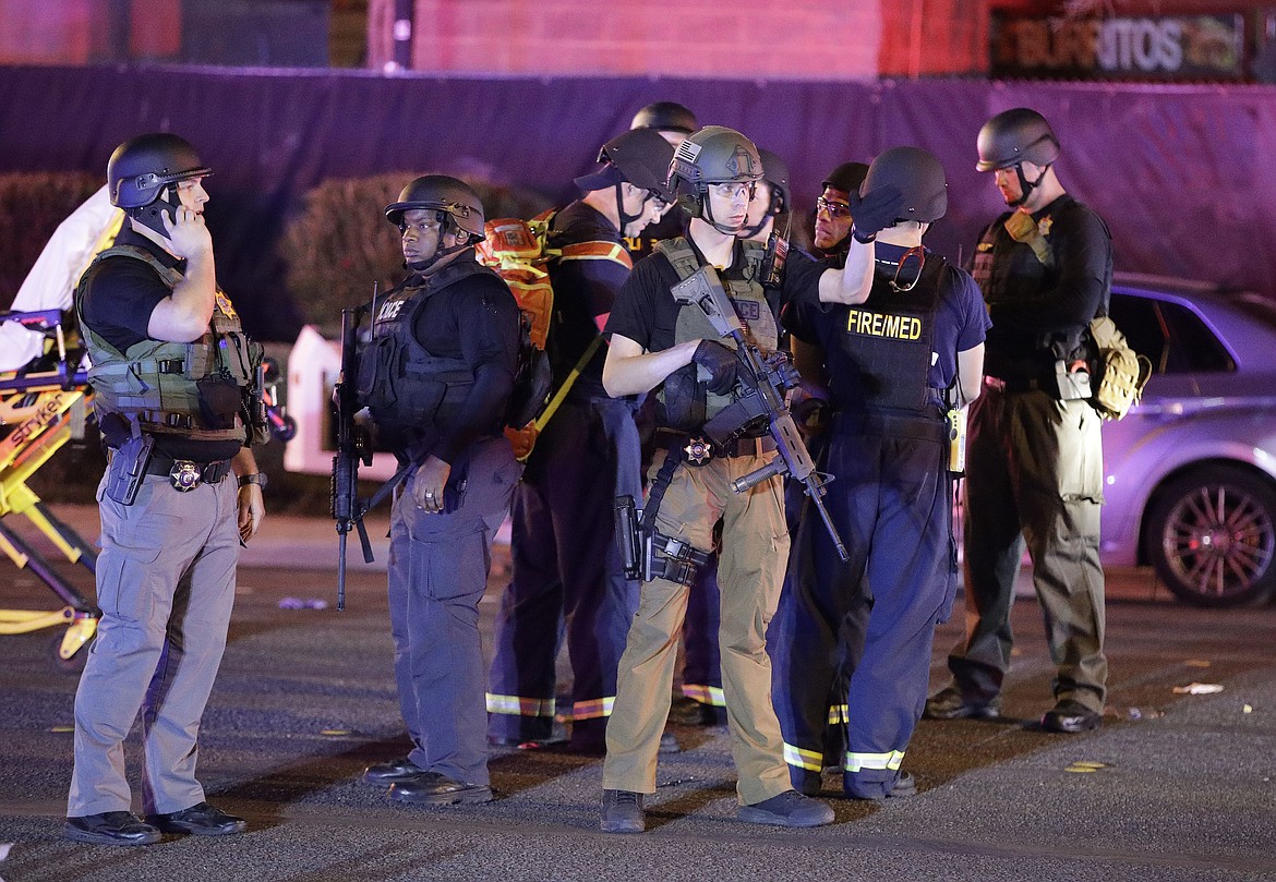 Police officers stand at the scene of a shooting near the Mandalay Bay resort and casino on the Las Vegas Strip, Monday, Oct. 2, 2017, in Las Vegas. Multiple victims were being transported to hospitals after a shooting late Sunday at a music festival on the Las Vegas Strip. (AP Photo/John Locher)