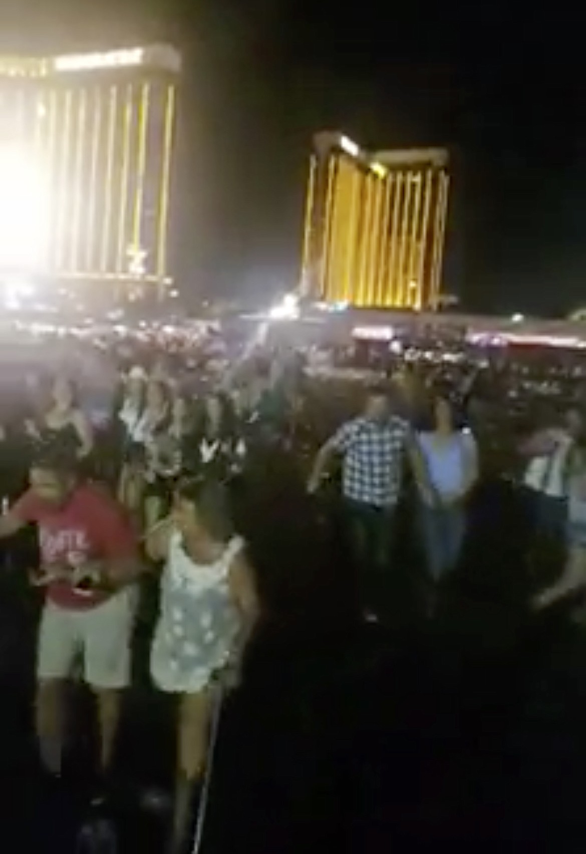 In this Sunday, Oct. 1, 2017 frame from video, people leave the scene of a deadly shooting in Las Vegas. Multiple victims were being transported to hospitals after a shooting late Sunday at a music festival on the Las Vegas Strip. (Shawn Kilgore via AP)