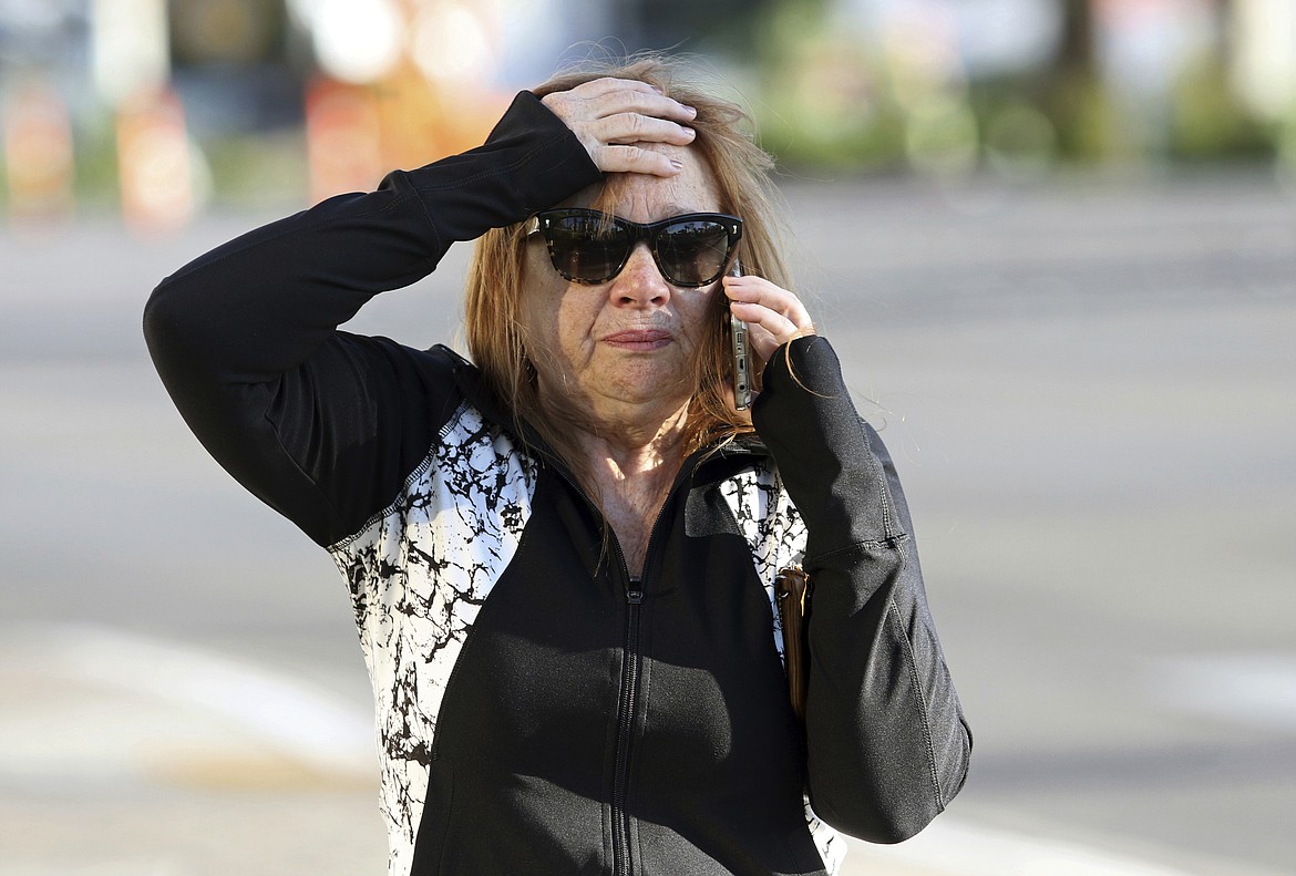 A woman speaks on the phone while walking along the Las Vegas Strip near Mandalay Bay hotel and casino Monday, Oct. 2, 2017, in Las Vegas. A mass shooting occurred late night Sunday at a music festival on the Las Vegas Strip. (AP Photo/Ronda Churchill)