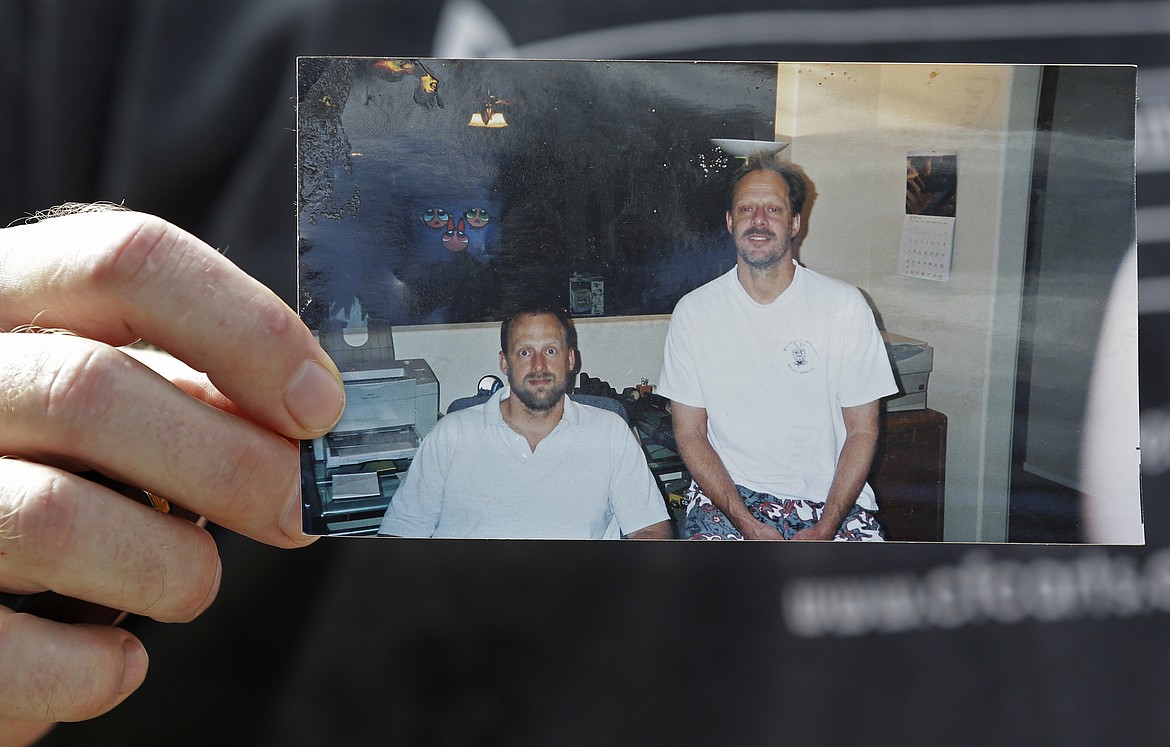 Eric Paddock holds a photo of him, at left, and his brother, Stephen Paddock, at right, outside his home, Monday, Oct. 2, 2017, in Orlando, Fla. Stephen Paddock opened fire on the Route 91 Harvest Festival on Sunday killing dozens and wounding hundreds. (AP Photo/John Raoux)