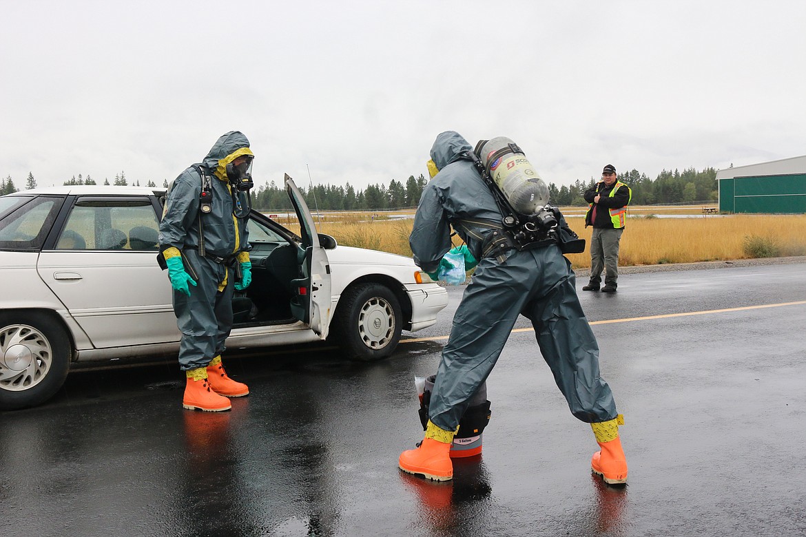 Above: Crews investigate the simulated crash vehicle with the white, powdery substance.

Left: North Bench Firefighters work together to set up a decontamination station.

Below: A decontamination exercise taking place in the rain.