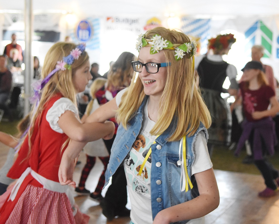 Josie Wathan, 14, along with Bella Star, 9, do the Chicken Dance Saturday afternoon at Great Northwest Oktoberfest in Depot Park. (Heidi Desch/Whitefish Pilot)