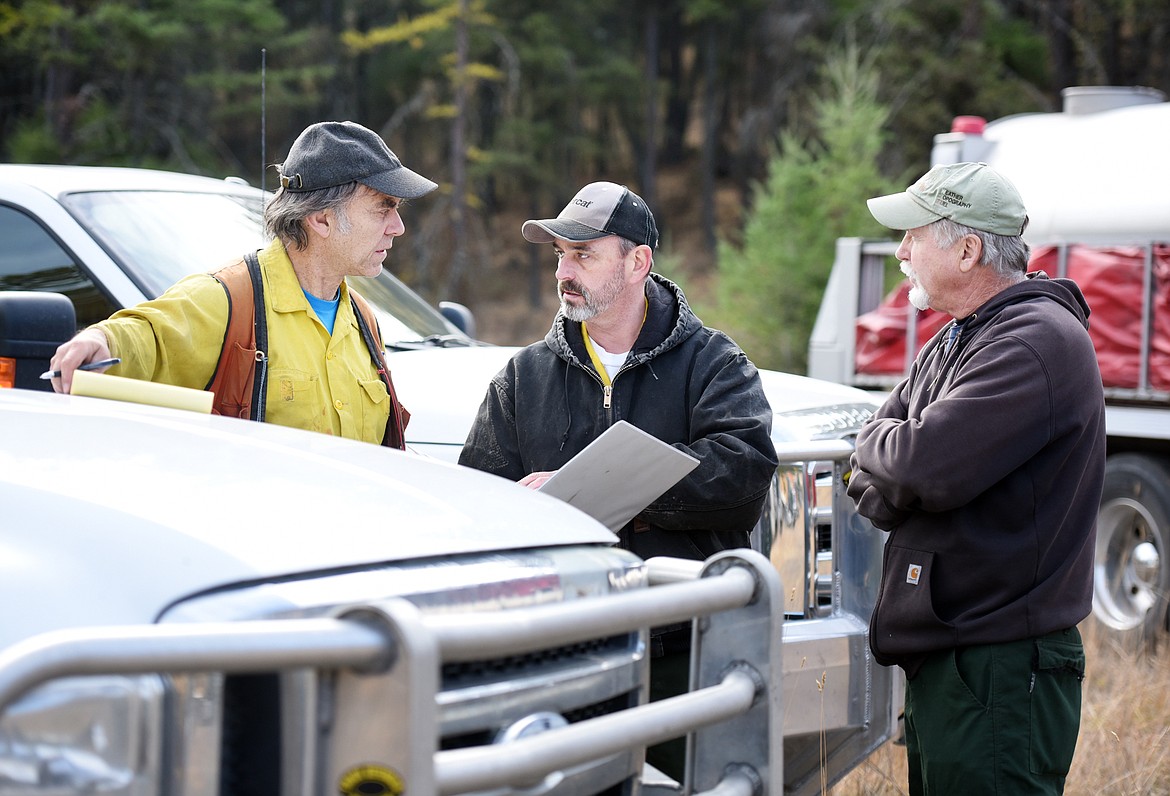 Pete Evans, left, and Bill Glaspey of the Department of Natural Resources and Conservation, talk with Rob Miller of James A. Slack Inc., logging company, about where to send resources for the Deer Run Fire near Foy&#146;s Lake on Wednesday morning, Oct. 18, west of Kalispell. (Brenda Ahearn/Daily Inter Lake)