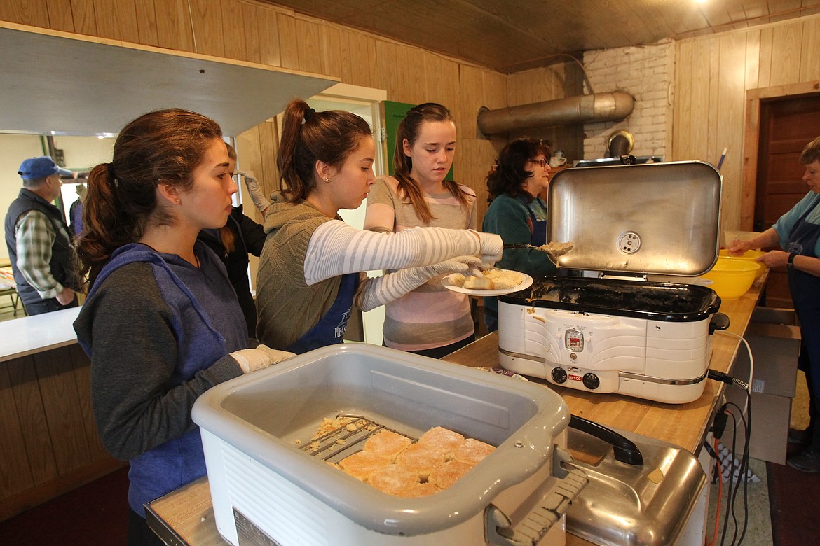 DEVIN HEILMAN/Press
Rita Klocko, 12, of Post Falls, dishes up homemade biscuits and gravy Saturday morning with the assistance of her sister, Maria, 14, left, and friend Madeline Goggin, 13. The young ladies volunteered to work in the kitchen of Pleasantview School during the Cowboy Breakfast, which serves as a major fundraiser for the Post Falls historic site. The Pleasantview Community Association has several projects in the works to restore the 1910 building and give it new life as a community center.