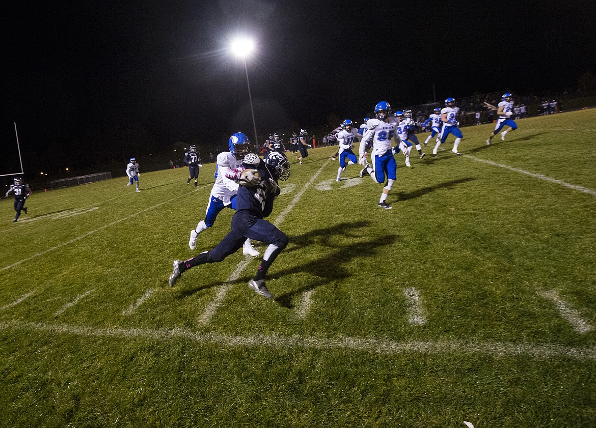 LOREN BENOIT/PressCoeur d'Alene cornerback Kyle Dewitt tries to tackle Lake City wide receiver Dusty Calligan near the sideline during Friday night's game at Lake City High School.