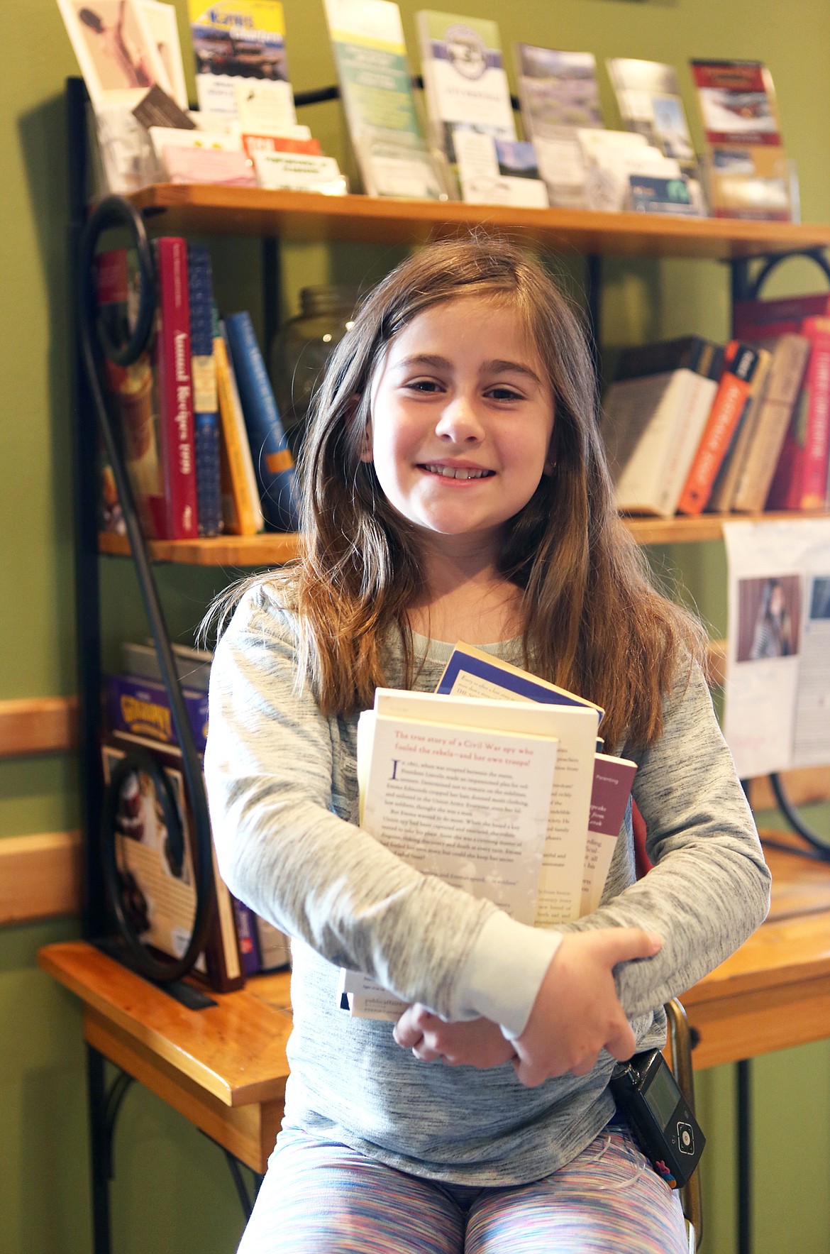 Courtney Rhoades, of Lakeside, is pictured in front of a used book display at Glacier Perks Coffee House. Proceeds from the sale of the books go toward purchasing a diabetic alert dog for Rhoades. (Mackenzie Reiss/Daily Inter Lake)