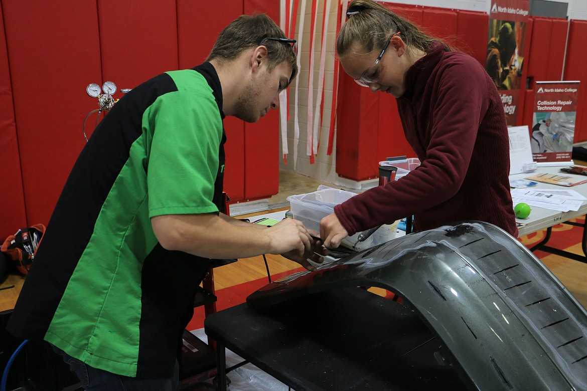 (Photo by MARY MALONE)
North Idaho College student Tre Higgins shows Sandpoint High School freshman Camille Caven the technique for plastic welding during the NIC Career-Technical Education Roadshow at SHS on Friday.