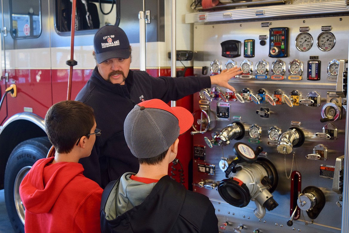 Charles H. Featherstone/Columbia Basin Herald
Moses Lake firefighter Eric Shurtz shows a couple of boys how a fire truck works at the annual Firefighters Breakfast on Saturday.