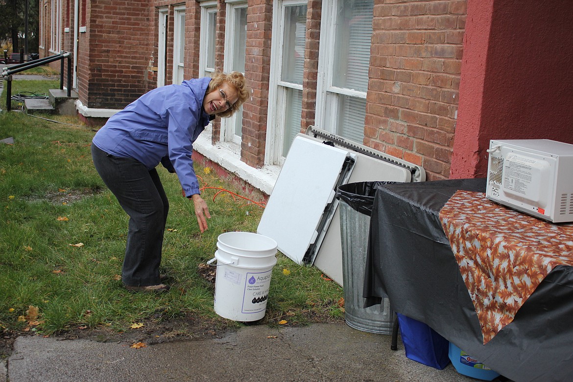 Chamber member Loie Turner puts a bucket under a stream of water falling from the roof as she manages to heat pretzels in a microwave on a table tucked under an eave during Sat. October 7 festivities.