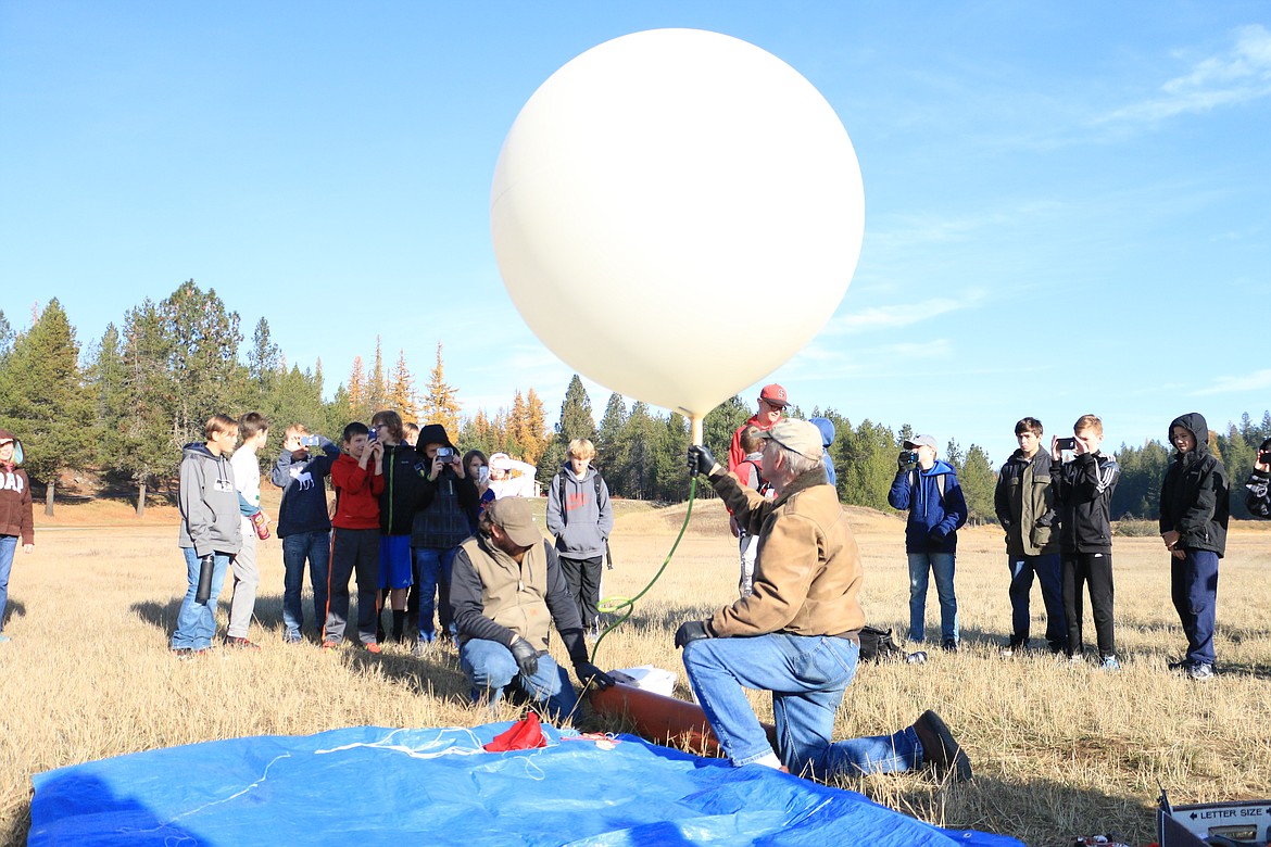 (Photo by MARY MALONE)
Students from Dinah Gaddie's Sandpoint Middle School class and Laura Spurway's Rathdrum gifted and talented class look on as Marty  Mueller, front right, and Ian Gaddie, front left, fill a 1,200 gram weather balloon with helium Friday in preparation for a near space balloon launch Friday as part of a Gizmo2Extremes project.