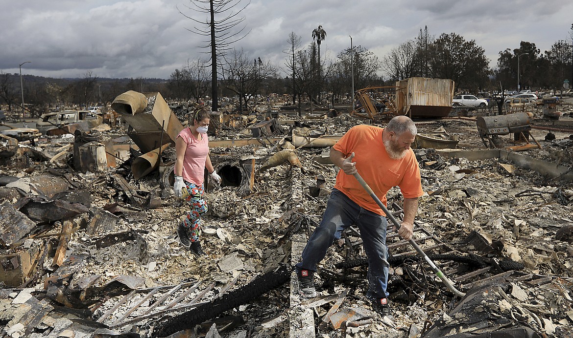 Sarah Boryszewski is helped by her father Gerald Peete as they dig for belongings in the remains of Boryszewski's home in Coffey Park, Friday Oct. 20, 2017 in Santa Rosa, Calif. Northern California residents who fled a wildfire in the dead of night with only minutes to spare returned to their neighborhoods Friday for the first time in nearly two weeks to see if anything was standing. (Kent Porter/The Press Democrat via AP)