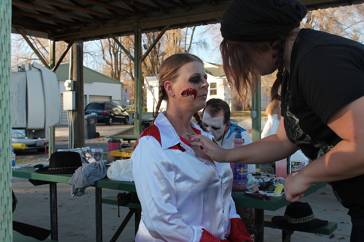 Joel Martin/Columbia Basin Herald
Destiny Sheriff, right, turns Christi Eakin of Lind into a decaying corpse for the Zombie Walk Saturday, while Ellis Cody touches up his makeup in the background.