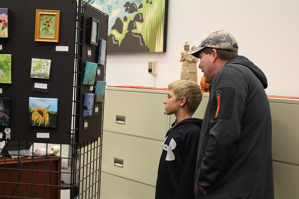 Cheryl Schweizer/Columbia Basin Herald
Art show patrons check the display at the artist reception for the miniature art show Tuesday.