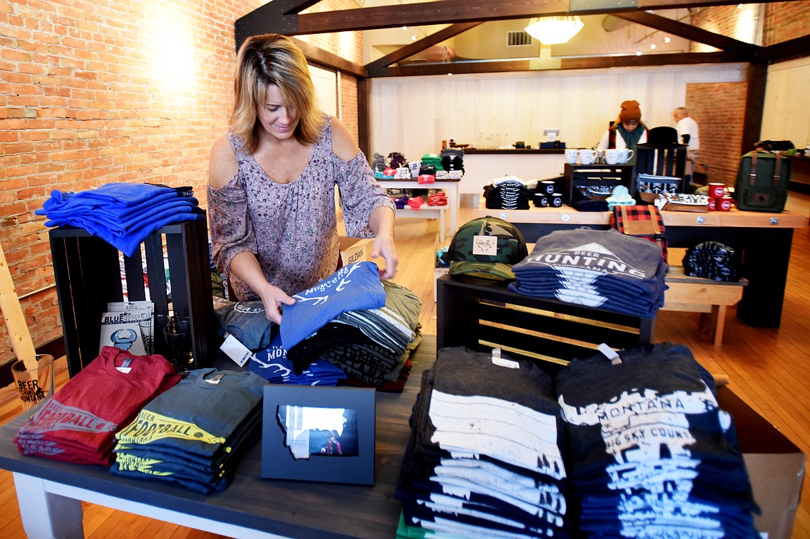 Wendy Gorman organizing stock before the grand opening of the new downtown location of The Montana Scene in Kalispell.(Brenda Ahearn/Daily Inter Lake)