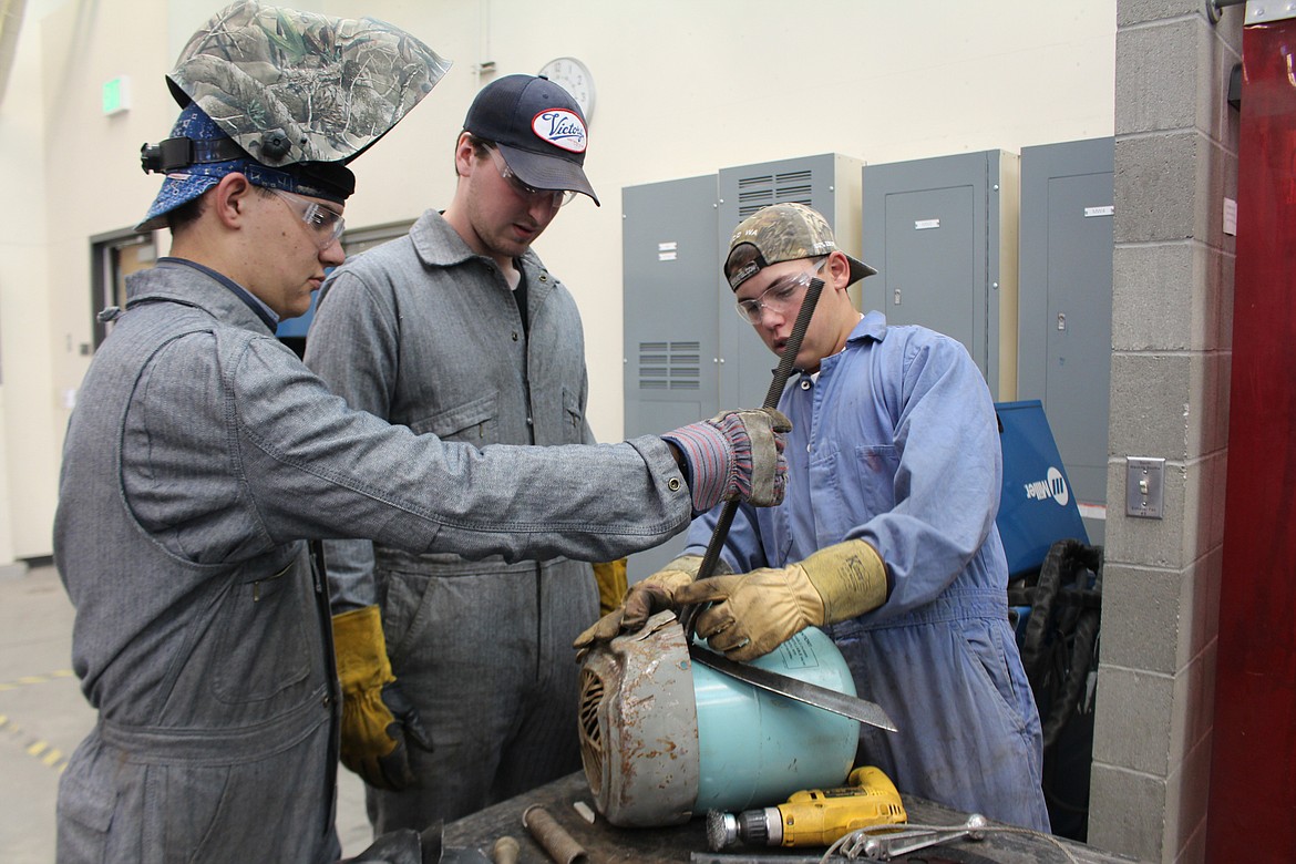 Cheryl Schweizer/Columbia Basin Herald
Members of the Kamiakin High School welding class discuss the finer points of their design at the Metal Art Competition Thursday at CB Tech.