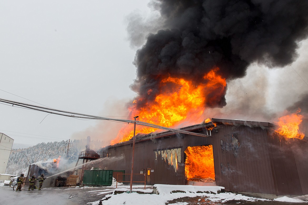 Three Libby firefighters try to knock down flames at SK Fingerjoint Sunday. (John Blodgett/The Western News)