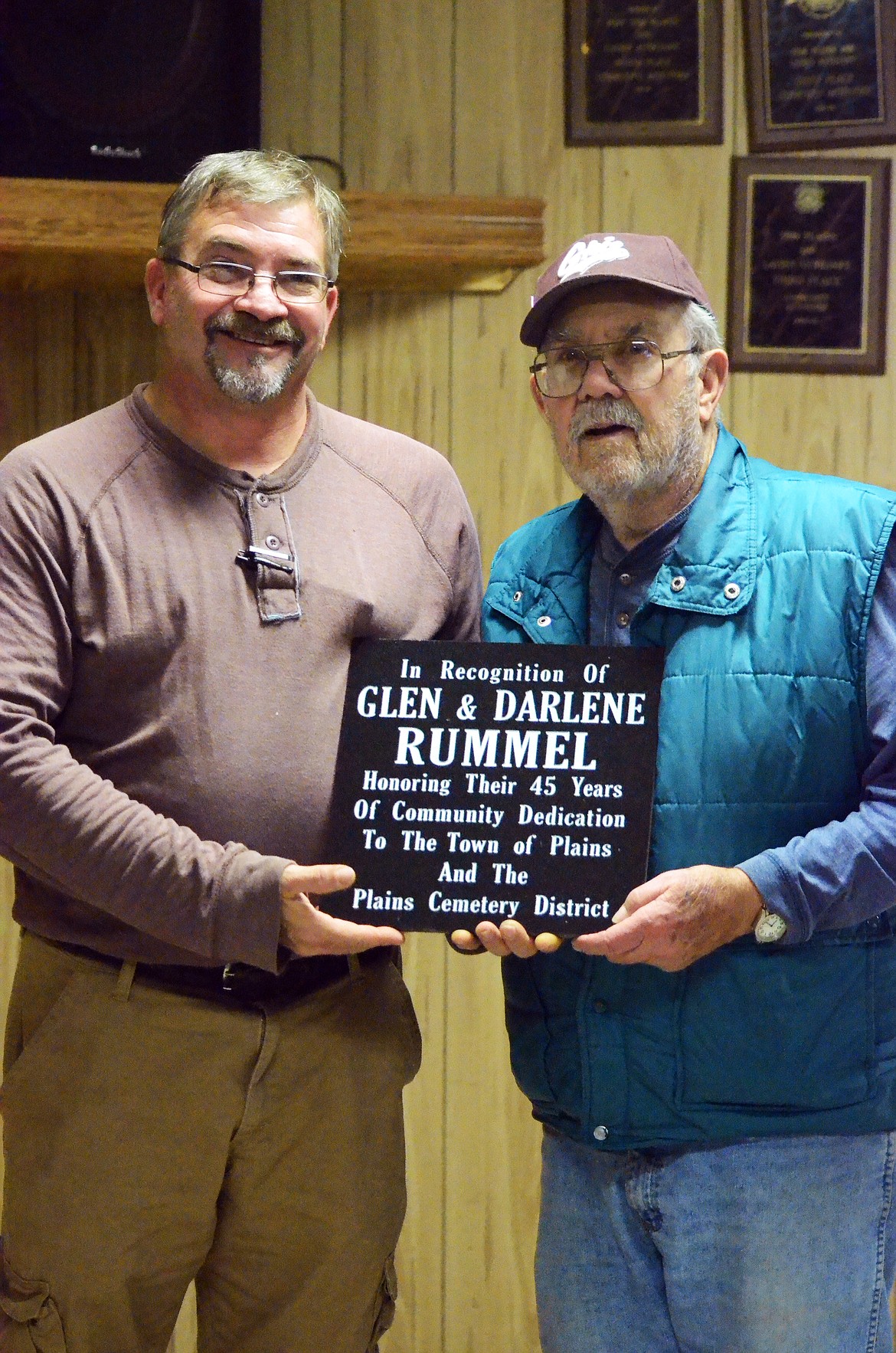 Plains Chief of Police Shawn Emmett, left, with Glen Rummel pose for a photo with the plaque awarded to Rummel and his wife Darlene for their outstanding service to their community. (Erin Jusseaume/ Clark Fork Valley Press)