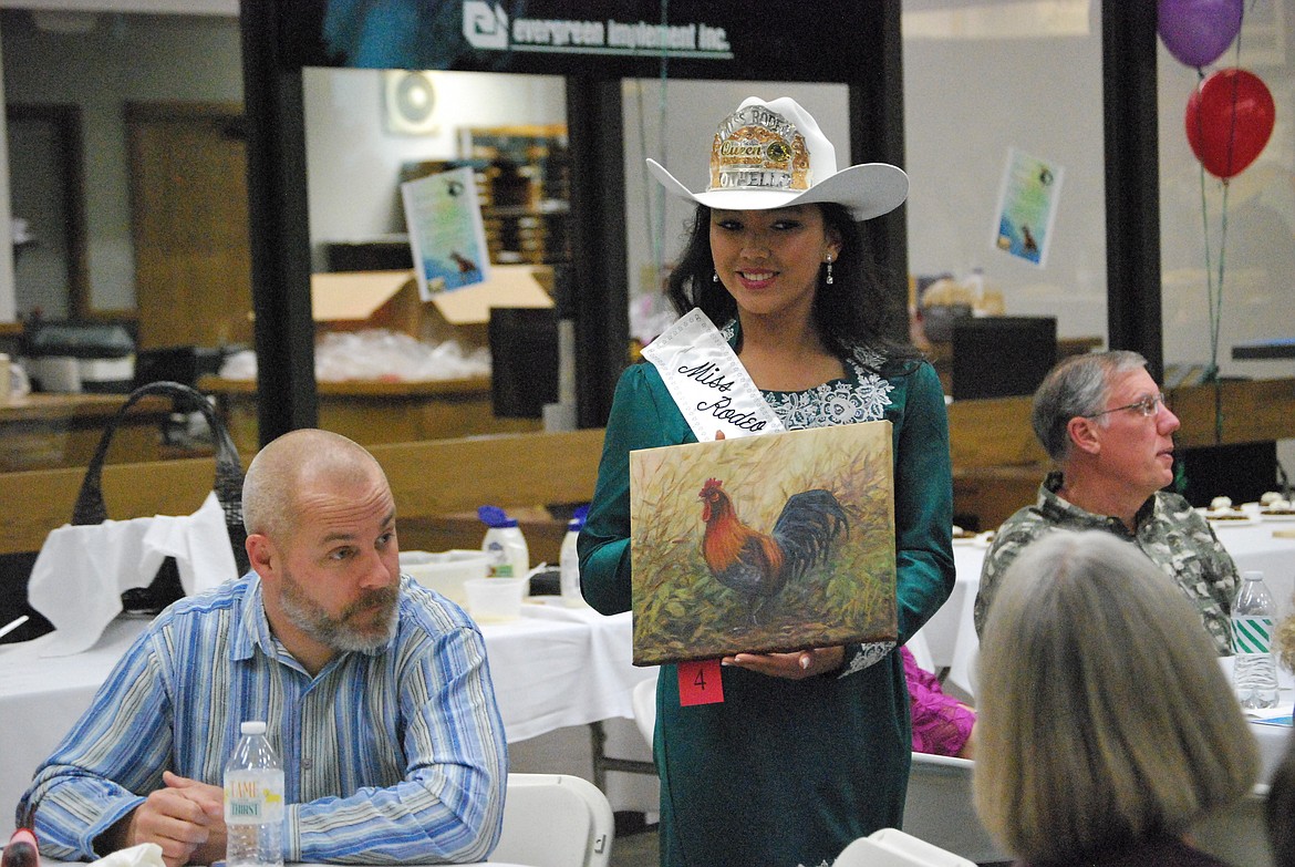 Bob Kirkpatrick/The Sun Tribune - Incoming Othello Rodeo Queen Sarah Wilson displays a painting up for bid by Moses Lake artist Susan Wapole, who was the Old Hotel Art Gallery Artist of the Month for September.