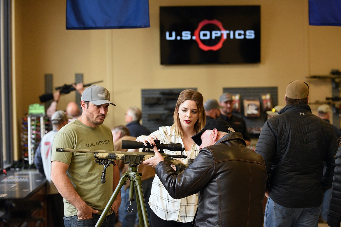 From left, Nick Gadarzi, a professional shooter for U.S. Optics and Kyleigh Cameron, sales and marketing for U.S. Optics, show Rod Samdahl, of Whitefish, a .308 bolt action rifle with a U.S. Optics B17 scope and a Manners carbon fiber stock at an open house event at U.S. Optics in Kalispell on Friday, Nov. 17. (Casey Kreider/Daily Inter Lake)