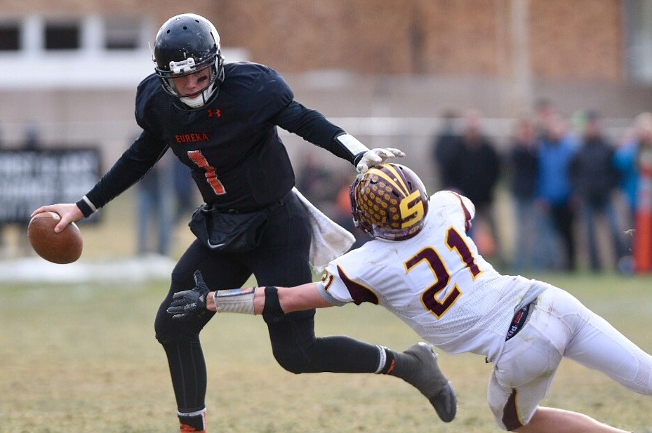 Eureka quarterback Garrett Graves stiff-arms Shelby defender Barrett Hansen on a scramble in the second quarter. (Casey Kreider photo/Daily Inter Lake)